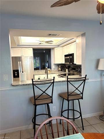 28230 Pine Haven Way, #68, Bonita Springs, FL 34135 Kitchen featuring kitchen peninsula, appliances with stainless steel finishes, white cabinets, and light tile patterned floors