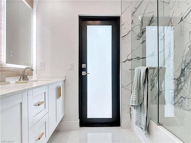 125 41st Ter, Cape Coral, FL 33904 Full bath featuring shower / bath combination with glass door and vanity