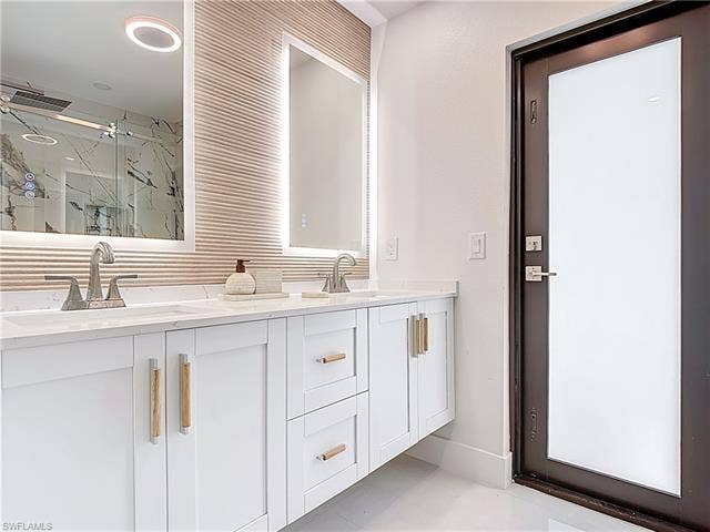 125 41st Ter, Cape Coral, FL 33904 Bathroom featuring a marble finish shower and double vanity