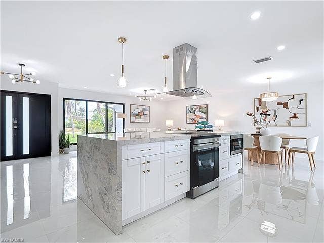 125 41st Ter, Cape Coral, FL 33904 Kitchen featuring island exhaust hood, stainless steel electric range oven, white cabinetry, light stone countertops, and pendant lighting