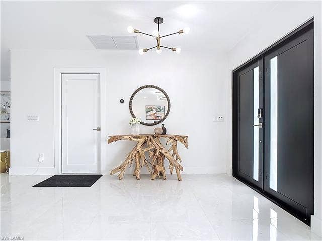 125 41st Ter, Cape Coral, FL 33904 Foyer featuring a chandelier and baseboards