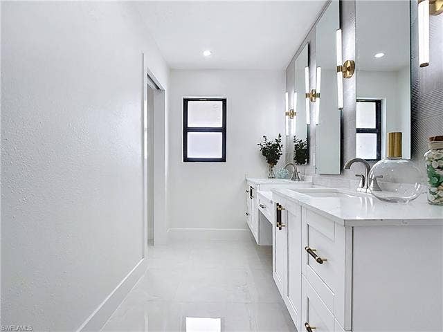 125 41st Ter, Cape Coral, FL 33904 Bathroom featuring baseboards, double vanity, and tile patterned flooring