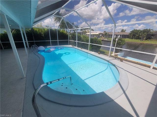 125 41st Ter, Cape Coral, FL 33904 Swimming pool with a patio, glass enclosure, a water view, and a sunroom