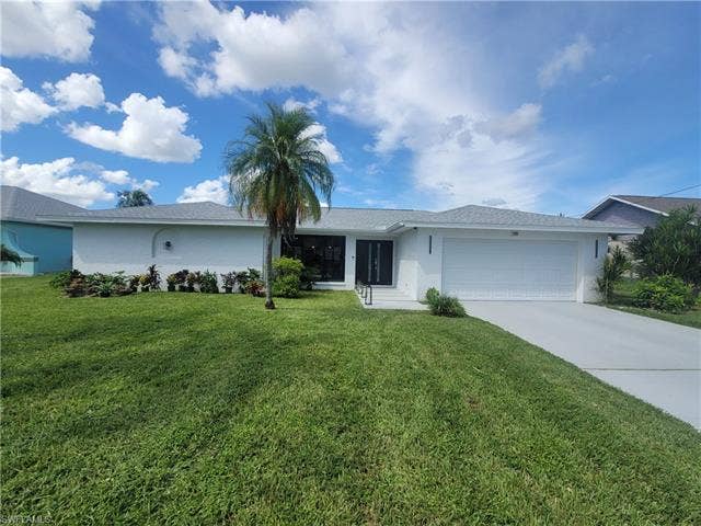 125 41st Ter, Cape Coral, FL 33904 Single story home featuring driveway, an attached garage, stucco siding, and a front yard