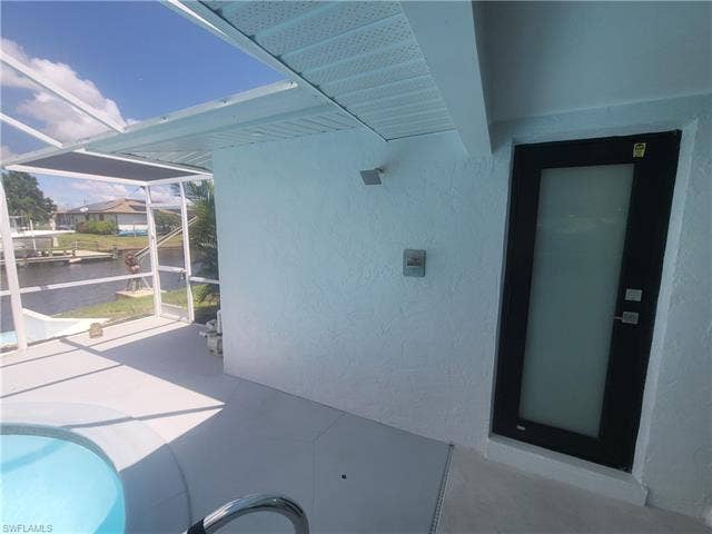 125 41st Ter, Cape Coral, FL 33904 View of patio featuring a sunroom, an outdoor pool, and a water view