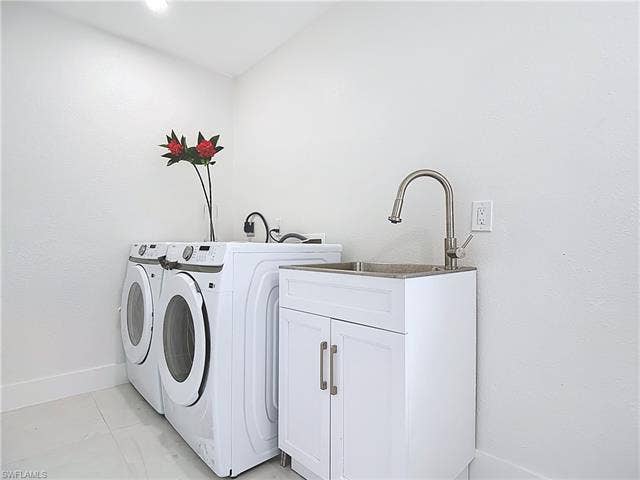 125 41st Ter, Cape Coral, FL 33904 Laundry room featuring washer and clothes dryer, cabinet space, and baseboards