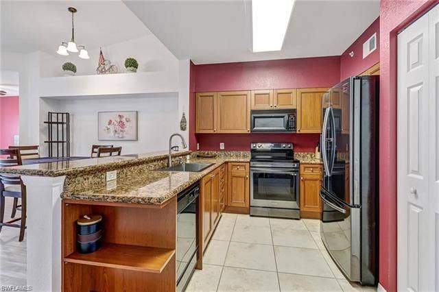 10127 Villagio Palms Way, #203, Estero, FL 33928 Kitchen with open shelves, black appliances, a kitchen breakfast bar, dark stone counters, and a peninsula