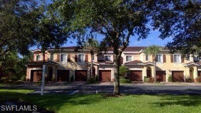 10127 Villagio Palms Way, #203, Estero, FL 33928 View of front of house featuring driveway, a front lawn, and an attached garage