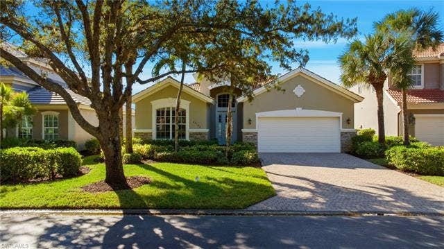 22140 Long Leaf Trail Dr, Estero, FL 34135 Mediterranean / spanish home with stone siding, decorative driveway, stucco siding, a front lawn, and a garage