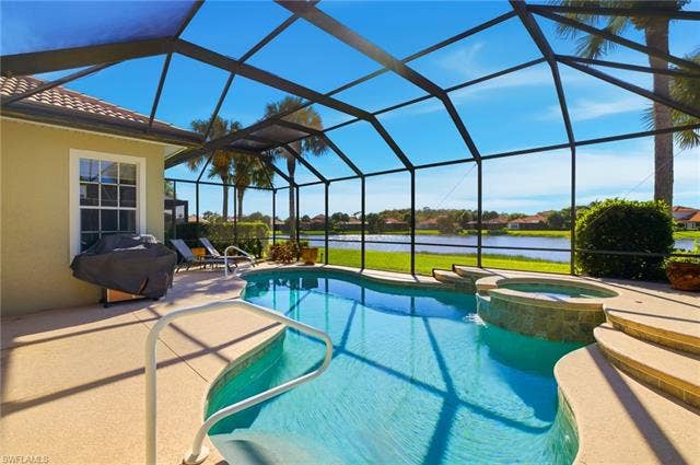 22140 Long Leaf Trail Dr, Estero, FL 34135 View of pool featuring a sunroom, a water view, a patio area, and glass enclosure