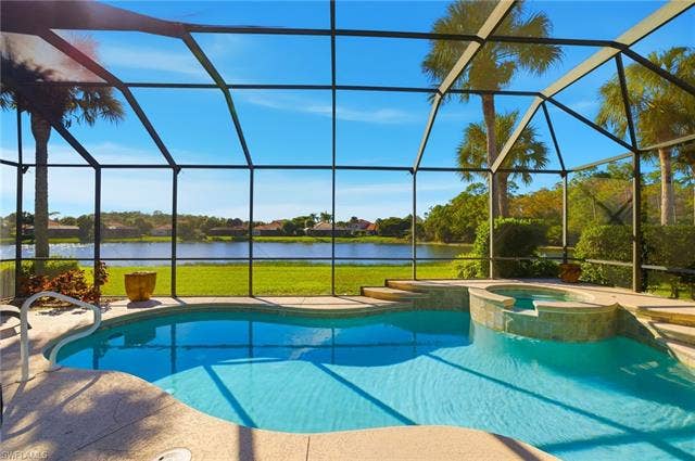 22140 Long Leaf Trail Dr, Estero, FL 34135 View of swimming pool with a sunroom, a water view, a pool with connected hot tub, a lanai, and a lawn