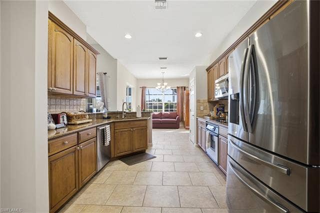 22140 Long Leaf Trail Dr, Estero, FL 34135 Kitchen featuring stainless steel appliances, a chandelier, dark stone countertops, tasteful backsplash, and hanging light fixtures