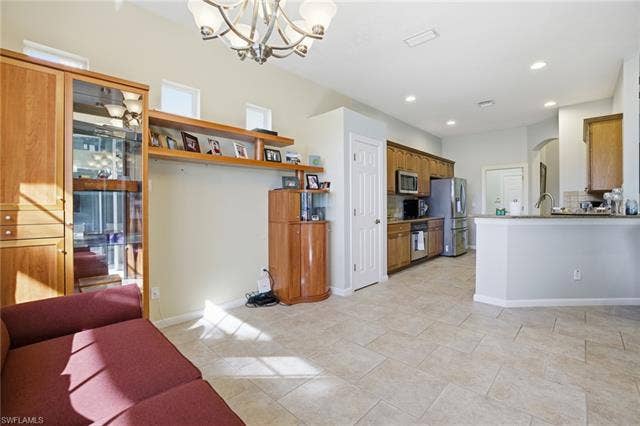 22140 Long Leaf Trail Dr, Estero, FL 34135 Kitchen featuring arched walkways, brown cabinets, a chandelier, appliances with stainless steel finishes, and backsplash