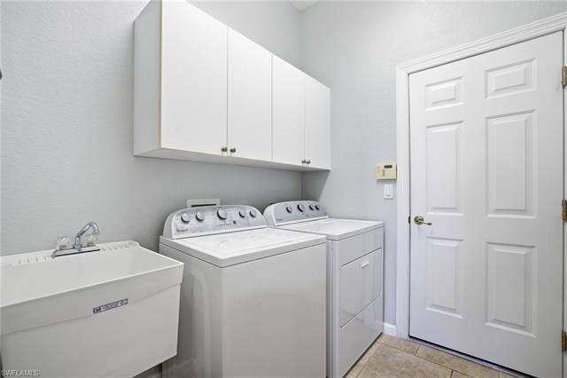 22140 Long Leaf Trail Dr, Estero, FL 34135 Washroom with cabinet space, washer and clothes dryer, light tile patterned flooring, and a textured wall