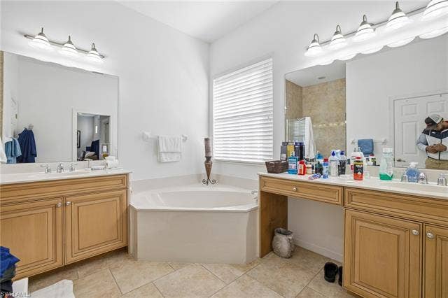 22140 Long Leaf Trail Dr, Estero, FL 34135 Bathroom with two vanities, a garden tub, light tile patterned floors, and walk in shower