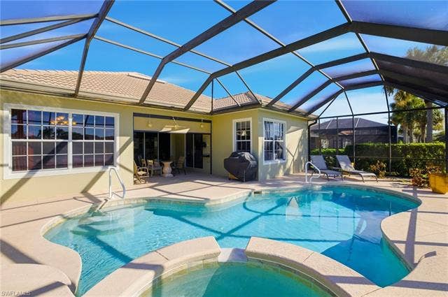 22140 Long Leaf Trail Dr, Estero, FL 34135 View of pool featuring a sunroom, a lanai, a patio, a pool with connected hot tub, and a grill