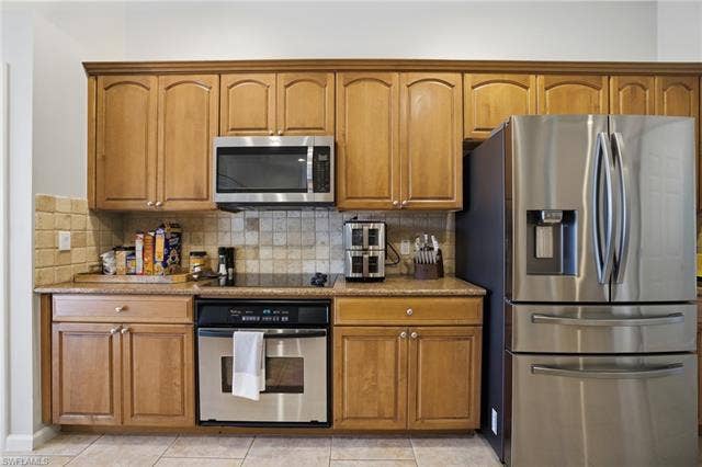 22140 Long Leaf Trail Dr, Estero, FL 34135 Kitchen featuring stainless steel appliances, brown cabinets, and light stone countertops