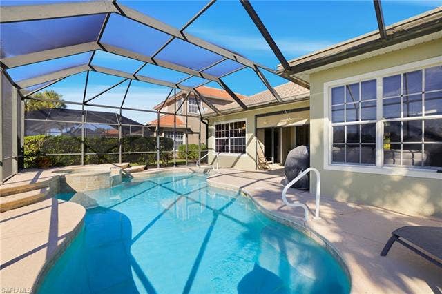 22140 Long Leaf Trail Dr, Estero, FL 34135 View of swimming pool featuring a patio, a sunroom, glass enclosure, and a pool with connected hot tub