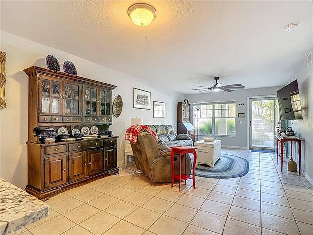 25735 Lake Amelia Way, #103, Bonita Springs, FL 34135 Living area featuring ceiling fan, light tile patterned flooring, and a textured ceiling