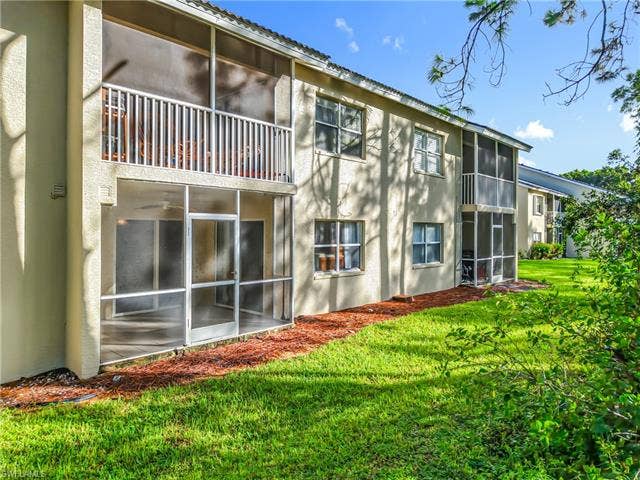 25735 Lake Amelia Way, #103, Bonita Springs, FL 34135 Rear view of house with a sunroom, a yard, stucco siding, and a balcony