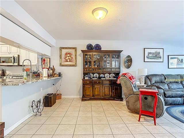 25735 Lake Amelia Way, #103, Bonita Springs, FL 34135 Living area with light tile patterned floors and a textured ceiling
