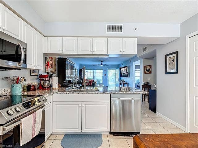 25735 Lake Amelia Way, #103, Bonita Springs, FL 34135 Kitchen featuring stainless steel appliances, white cabinets, light tile patterned flooring, and light stone countertops
