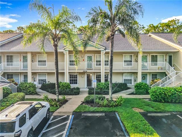 25735 Lake Amelia Way, #103, Bonita Springs, FL 34135 View of building exterior featuring uncovered parking and stairs