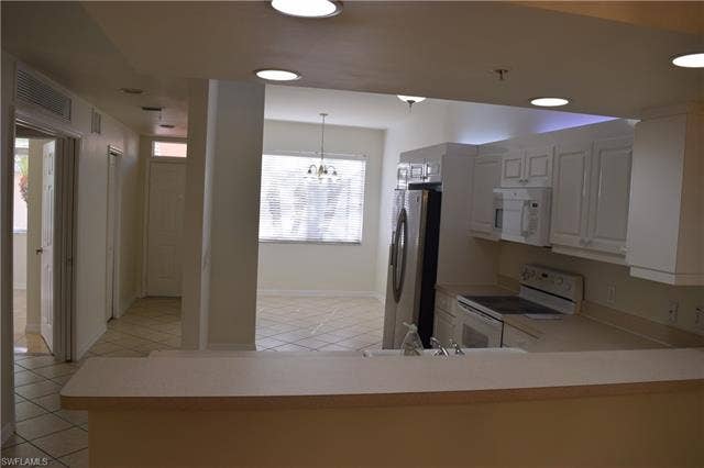 2350 Hidden Lake Ct, #8513, Naples, FL 34112 Kitchen featuring white cabinetry, white appliances, light countertops, light tile patterned flooring, and hanging light fixtures