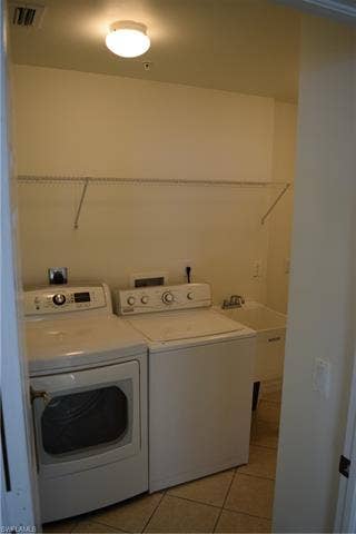 2350 Hidden Lake Ct, #8513, Naples, FL 34112 Laundry area with light tile patterned floors and washer and clothes dryer