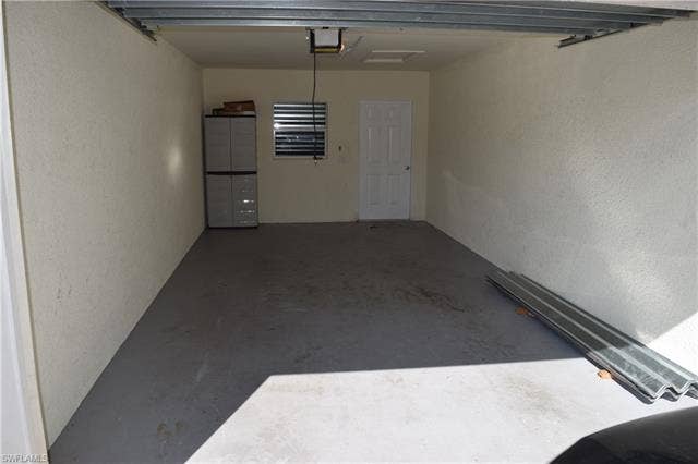 2350 Hidden Lake Ct, #8513, Naples, FL 34112 Garage with a textured wall and a garage door opener