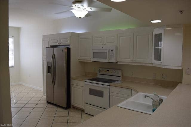 2350 Hidden Lake Ct, #8513, Naples, FL 34112 Kitchen with white appliances, light countertops, a ceiling fan, light tile patterned floors, and white cabinets