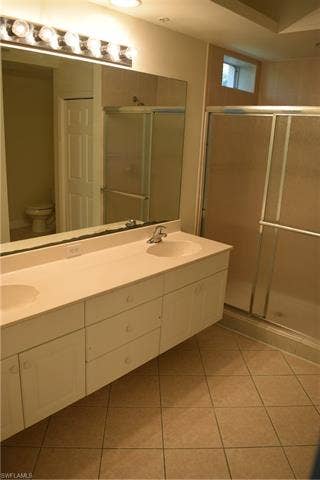 2350 Hidden Lake Ct, #8513, Naples, FL 34112 Bathroom with a shower stall, double vanity, and light tile patterned floors