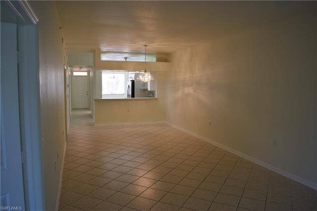 2350 Hidden Lake Ct, #8513, Naples, FL 34112 Empty room featuring light tile patterned floors and a chandelier