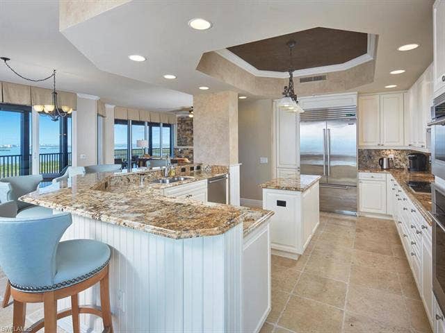 23750 Via Trevi Way, #2001, Estero, FL 34134 Kitchen featuring a center island, white cabinets, hanging light fixtures, light stone countertops, and a chandelier