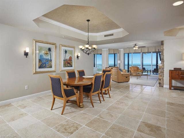 23750 Via Trevi Way, #2001, Estero, FL 34134 Dining room with crown molding, a chandelier, a tray ceiling, ceiling fan, and light tile patterned floors