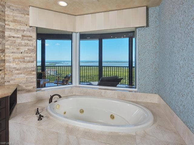 23750 Via Trevi Way, #2001, Estero, FL 34134 Bathroom featuring a whirlpool tub, healthy amount of natural light, wallpapered walls, and a water view