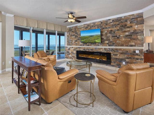 23750 Via Trevi Way, #2001, Estero, FL 34134 Living area featuring a fireplace, crown molding, and a ceiling fan