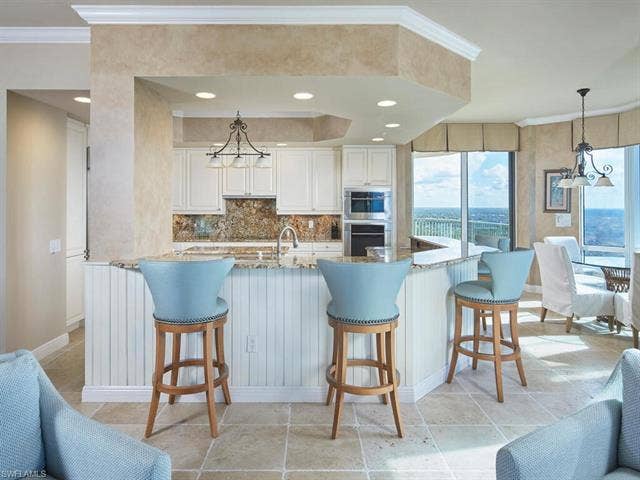 23750 Via Trevi Way, #2001, Estero, FL 34134 Kitchen with a chandelier, crown molding, light stone countertops, white cabinetry, and backsplash