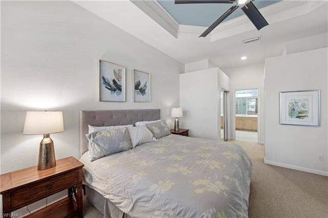 14546 Speranza Way, Bonita Springs, FL 34135 Bedroom with light colored carpet, ensuite bathroom, a tray ceiling, a ceiling fan, and recessed lighting