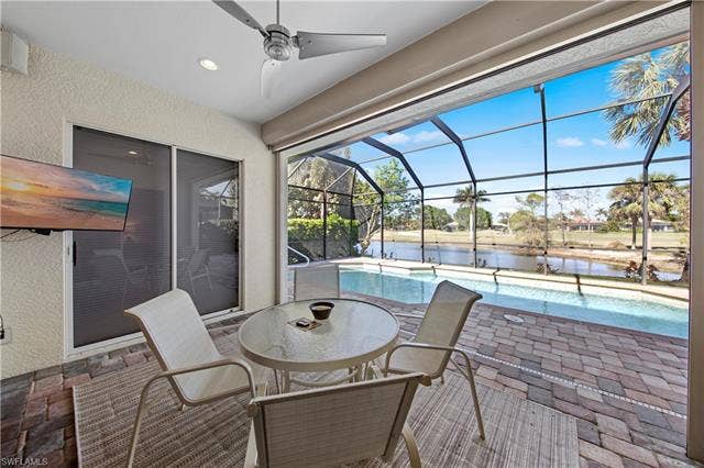 14546 Speranza Way, Bonita Springs, FL 34135 View of patio with an outdoor pool, a lanai, a water view, outdoor dining space, and a sunroom