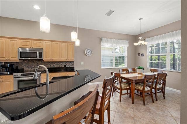 14546 Speranza Way, Bonita Springs, FL 34135 Kitchen with a breakfast bar, light tile patterned floors, appliances with stainless steel finishes, backsplash, and decorative light fixtures