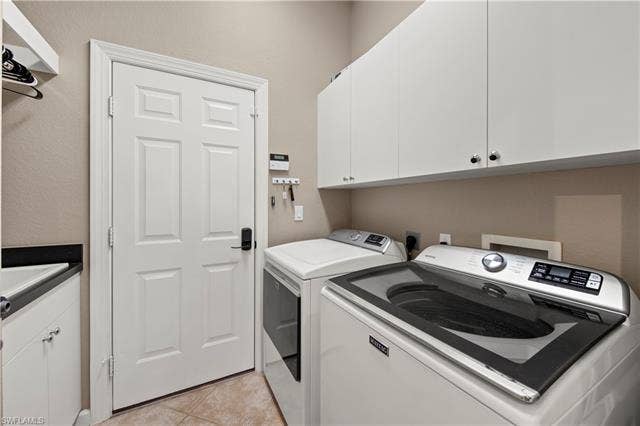 14546 Speranza Way, Bonita Springs, FL 34135 Laundry room featuring cabinet space, light tile patterned floors, and independent washer and dryer