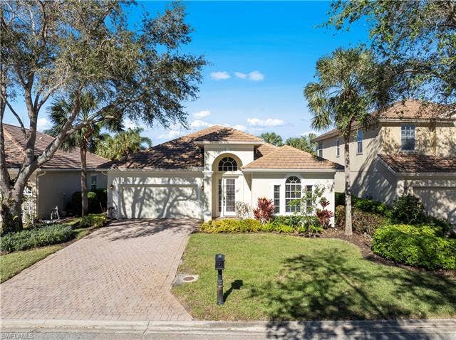 14546 Speranza Way, Bonita Springs, FL 34135 Mediterranean / spanish home featuring stucco siding, decorative driveway, a garage, a front yard, and a tiled roof