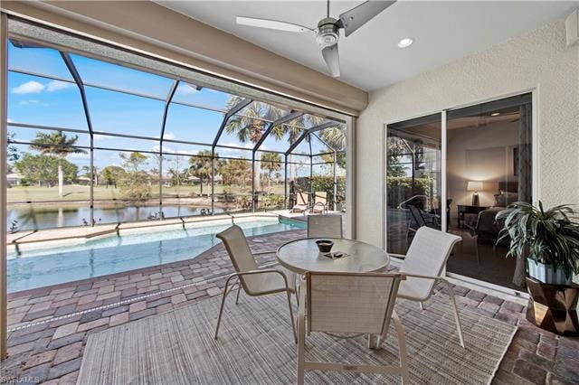 14546 Speranza Way, Bonita Springs, FL 34135 View of patio with an outdoor pool, a lanai, a water view, a ceiling fan, and a sunroom