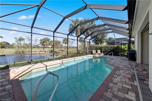 14546 Speranza Way, Bonita Springs, FL 34135 Outdoor pool with a sunroom, a patio, glass enclosure, a grill, and a water view
