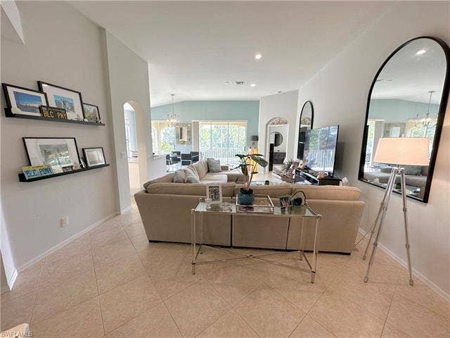 23007 Lone Oak Dr, Estero, FL 33928 Living room with a chandelier, arched walkways, lofted ceiling, and light tile patterned floors