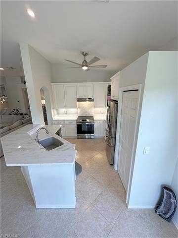 23007 Lone Oak Dr, Estero, FL 33928 Kitchen featuring stainless steel appliances, white cabinets, light stone countertops, light tile patterned flooring, and open floor plan