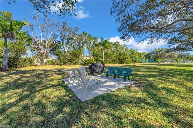 7320 Glenmoor Ln, #2304, Naples, FL 34104 View of green lawn featuring a patio area and view of scattered trees