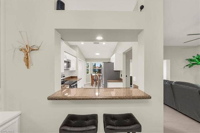 7320 Glenmoor Ln, #2304, Naples, FL 34104 Kitchen featuring white cabinets, stainless steel appliances, recessed lighting, open floor plan, and a kitchen breakfast bar