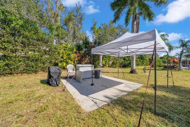 7320 Glenmoor Ln, #2304, Naples, FL 34104 View of grassy yard featuring a patio area and view of scattered trees